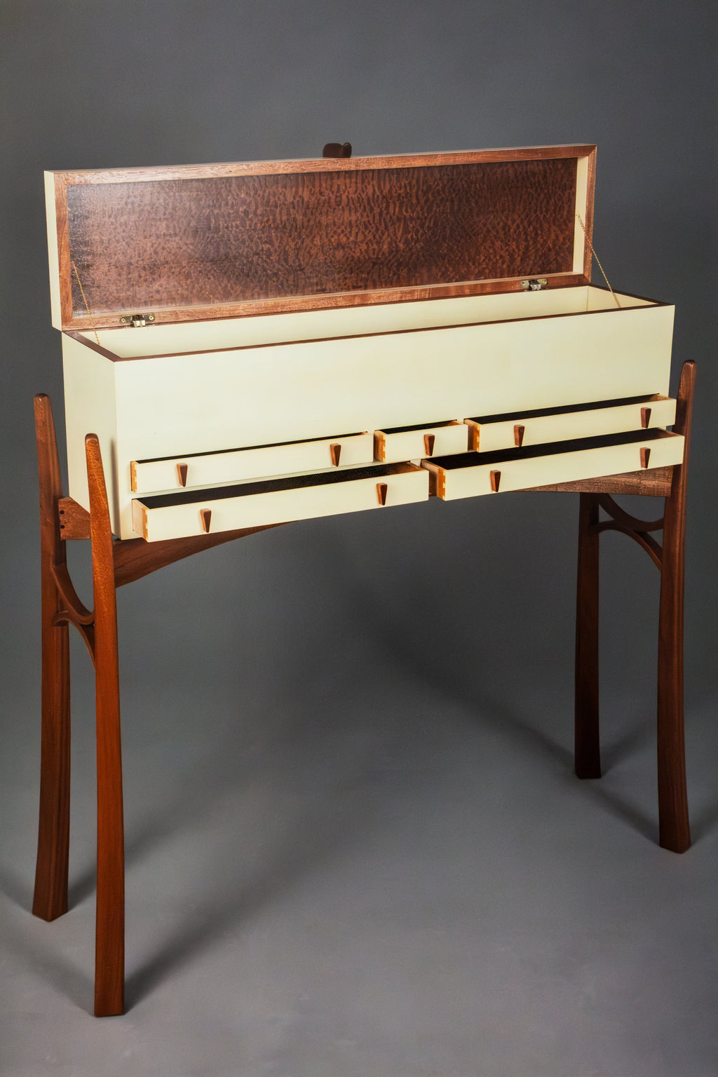 A mid-century modern writing desk with a cream-colored drawer-front body, a dark brown wood grain open hutch on top, and a matching dark brown wood frame and legs, shown against a neutral gray studio background.