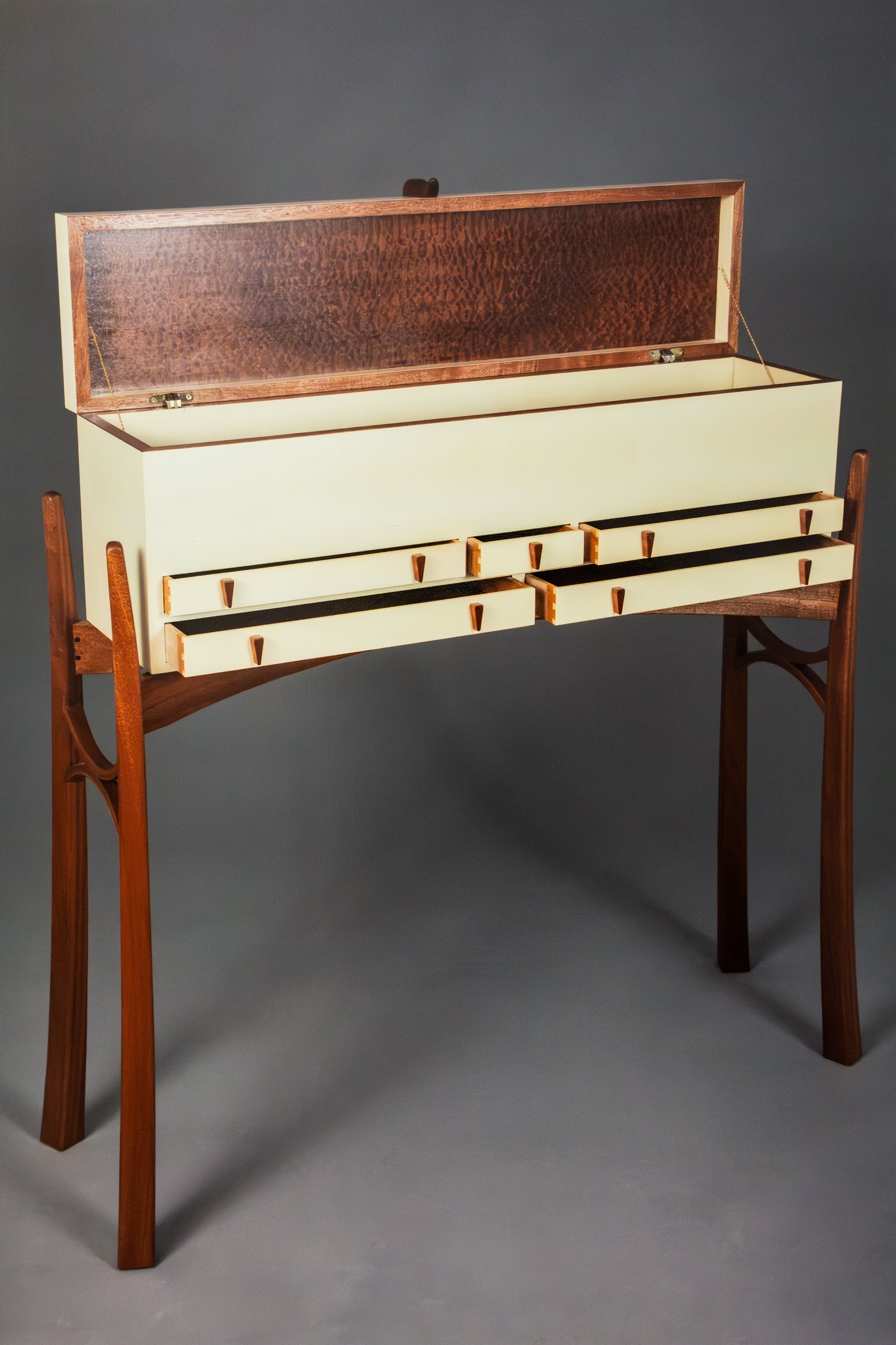 A mid-century modern writing desk with a cream-colored drawer-front body, a dark brown wood grain open hutch on top, and a matching dark brown wood frame and legs, shown against a neutral gray studio background.